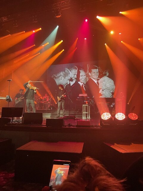 Stage view from the audience with violin imagery on screen &mdash; first concert, Mein Schiff 1, 29 April 2026