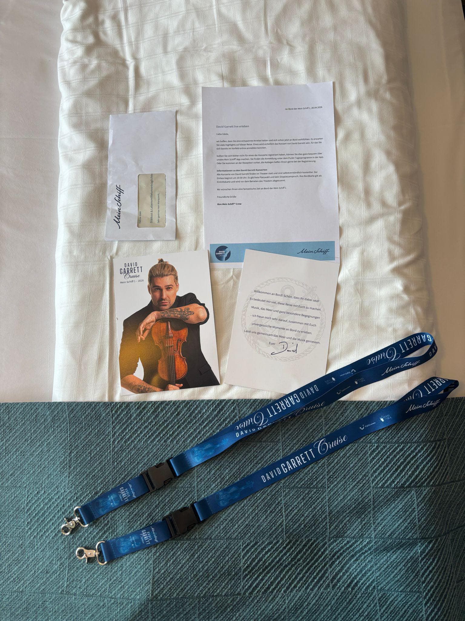 Welcome materials in the cabin — letter, postcard and lanyards, David Garrett Cruise, April 2026